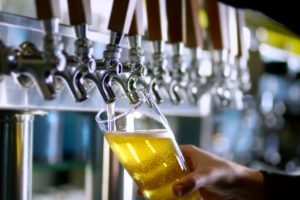 Tall glass with of beer being prepared to be served.